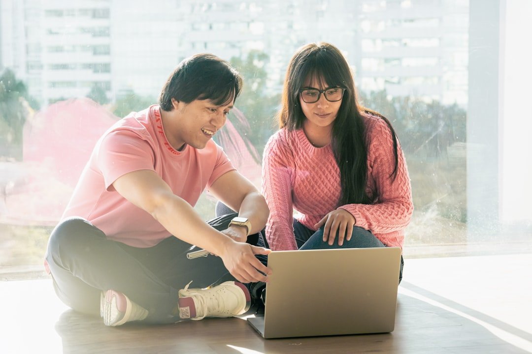 Photo by Julio Lopez - RobHillman.AI A man and woman sitting on the floor looking at a laptop
