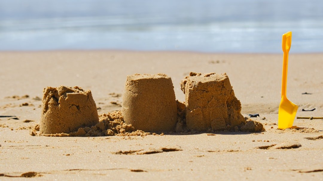 Photo by Phillip Flores - RobHillman.AI a sand castle on a beach with a shovel